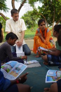 William Tucker, President of Charity United, works with a local tutor to educate children in a slum in India.